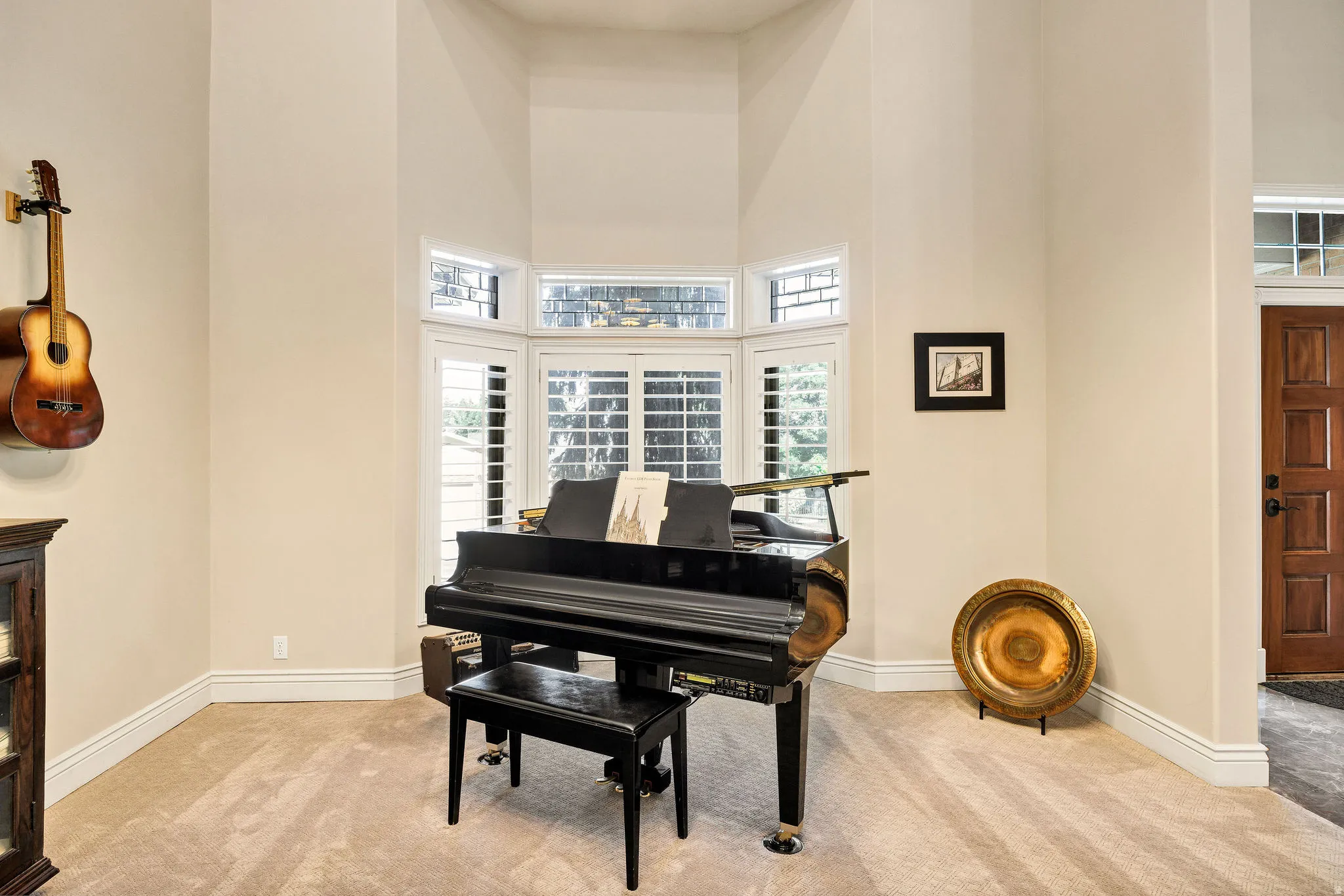 Bay window with custom plantation shutters, upper transom windows, vaulted ceilings, and plush carpeting