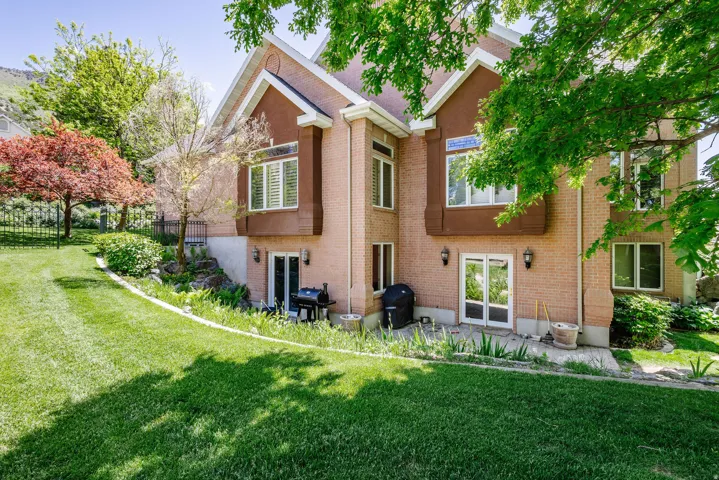 Brick exterior with multiple transom windows, an expansive lawn, and mature trees
