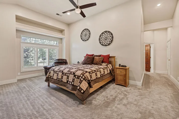 Recessed window alcove with plantation shutters, ceiling fan, carpeted flooring, and a built-in recessed niche