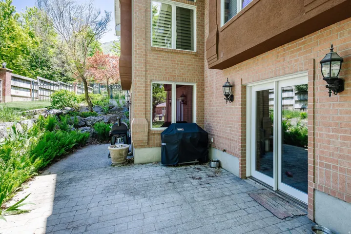 Brick exterior featuring paver patio, established landscaping, and wall-mounted exterior lighting
