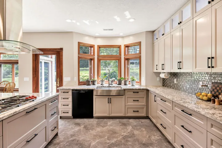 Kitchen featuring recessed lighting, light-colored cabinetry with dark hardware, granite countertops, and a mosaic tile backsplash