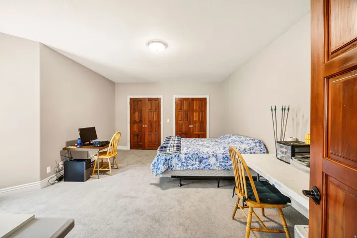 Spacious bedroom suite with carpet flooring, multiple wood-finish closet doors, and recessed ceiling lighting