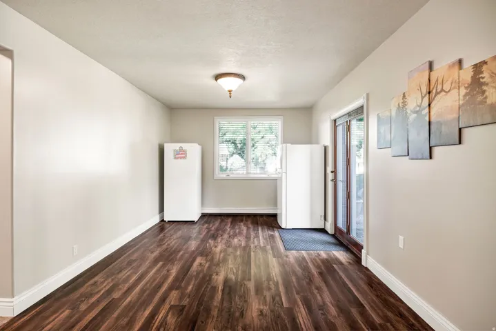 Wood-finish flooring, white trim, recessed window with blinds, and white walls