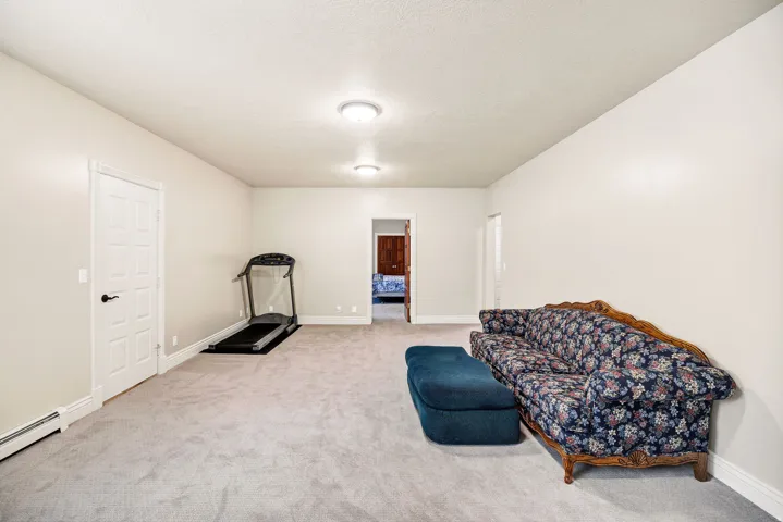 Spacious room with light gray carpeting, recessed lighting, and a paneled white door