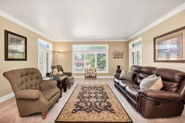 Spacious room with crown molding, light-toned wall paint, and wood-finish flooring