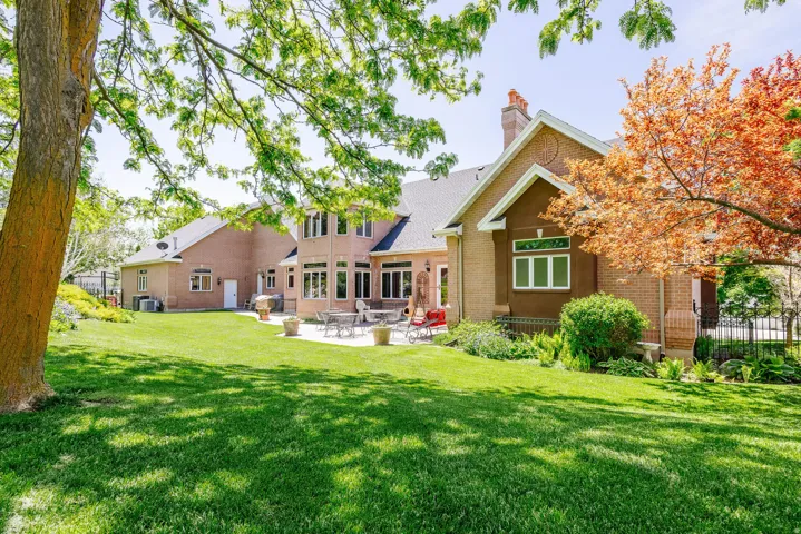 Expansive lawn with mature trees and a paved patio area