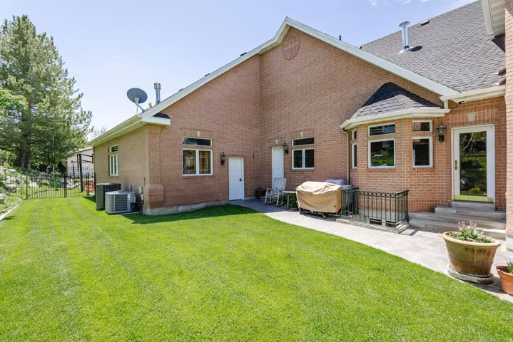 Expansive lawn area, brick exterior, bay window, exterior door, and paved patio