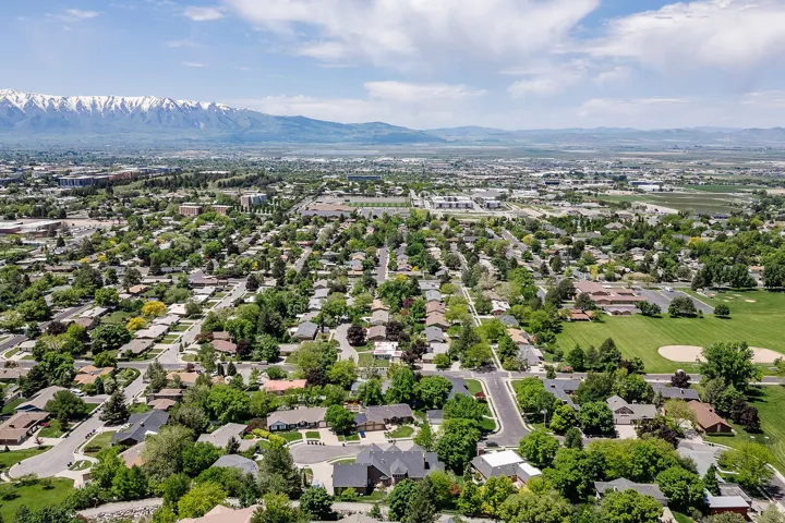 Established residential area with tree-lined streets, a prominent baseball field, and a distant mountain range featuring snow-capped peaks