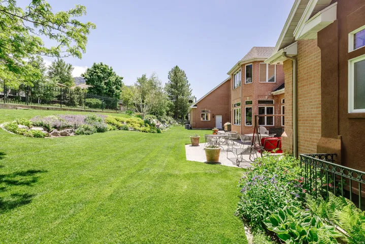 Expansive green lawn, established landscaping, paver patio, brick exterior, and multiple windows