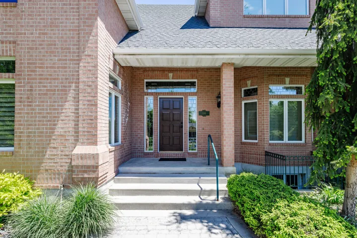 Brick exterior with a covered porch, concrete steps, and a paneled entry door with sidelights