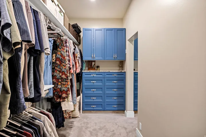 Custom blue cabinetry with silver hardware, integrated shelving, and recessed ceiling lighting