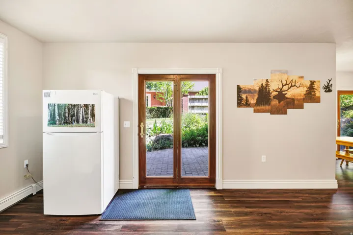 Wood-finish flooring, light neutral wall color, and wood-framed glass French doors opening to a brick patio
