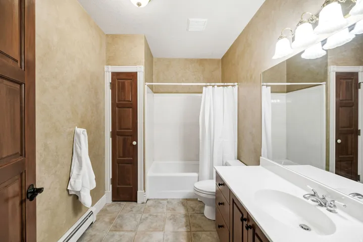 Full bathroom featuring a single vanity with dark wood-finish cabinetry, a white countertop, and an integrated sink
