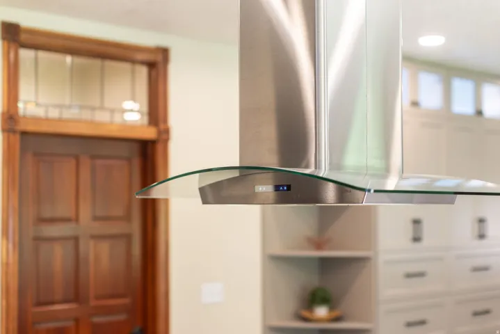 Stainless steel range hood with a curved glass canopy