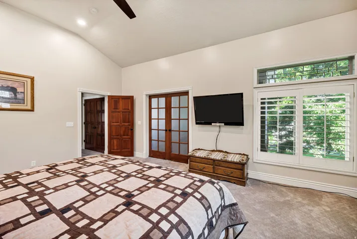 Vaulted ceiling with recessed lighting, double French doors, wood-finish interior door, and window with plantation shutters