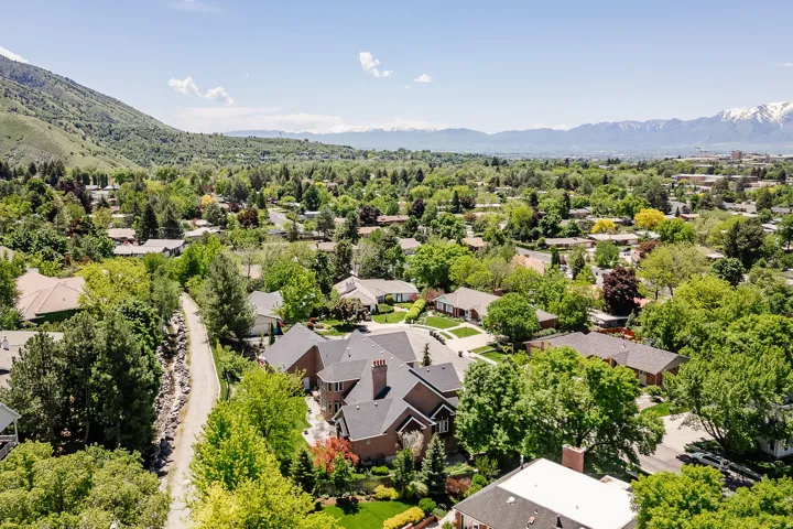 Residential neighborhood with mature trees, mountain backdrop, and paved pathways