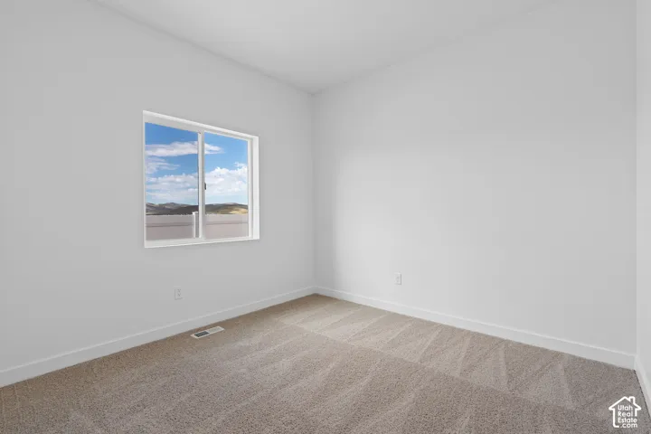 Neutral wall color with carpet flooring and a sliding window