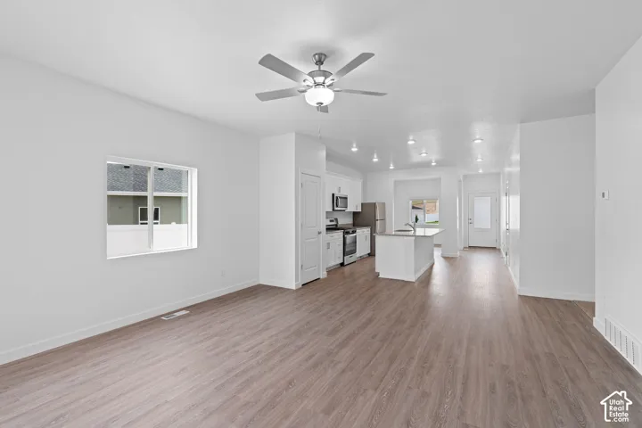 Open-concept living area featuring wood-finish flooring, recessed lighting, and a ceiling fan