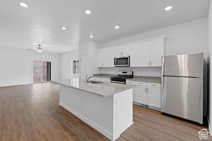 Modern kitchen featuring stainless steel appliances, white cabinetry with ample storage, granite countertops, and a center island with breakfast bar