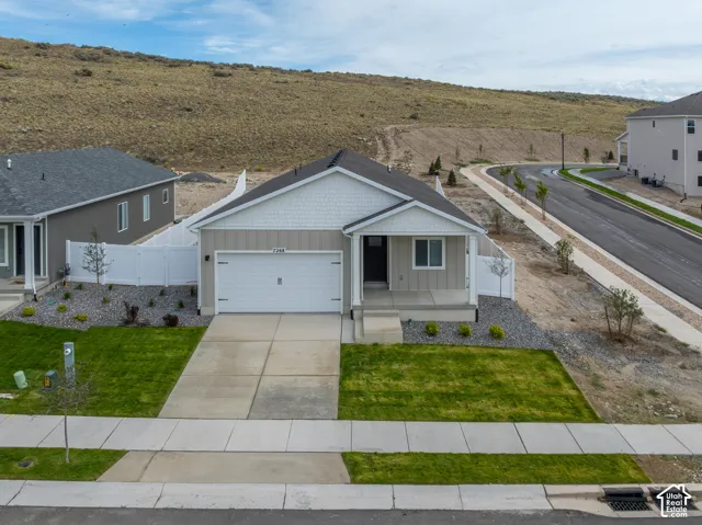 Single-story residence featuring a two-car garage, front porch, and white fencing