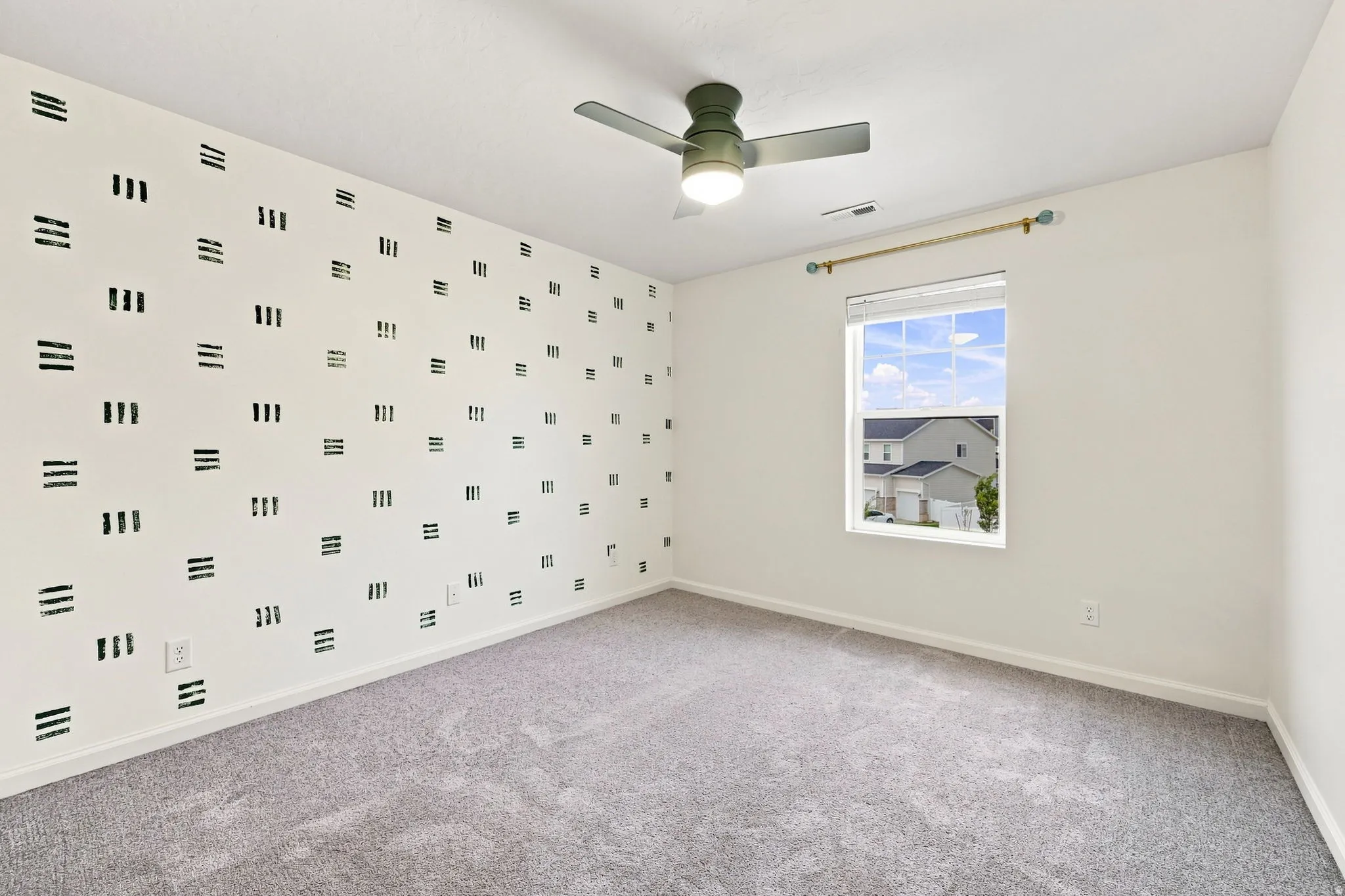 Plush carpet flooring, a decorative accent wall, ceiling fan with integrated lighting, and a window with blinds