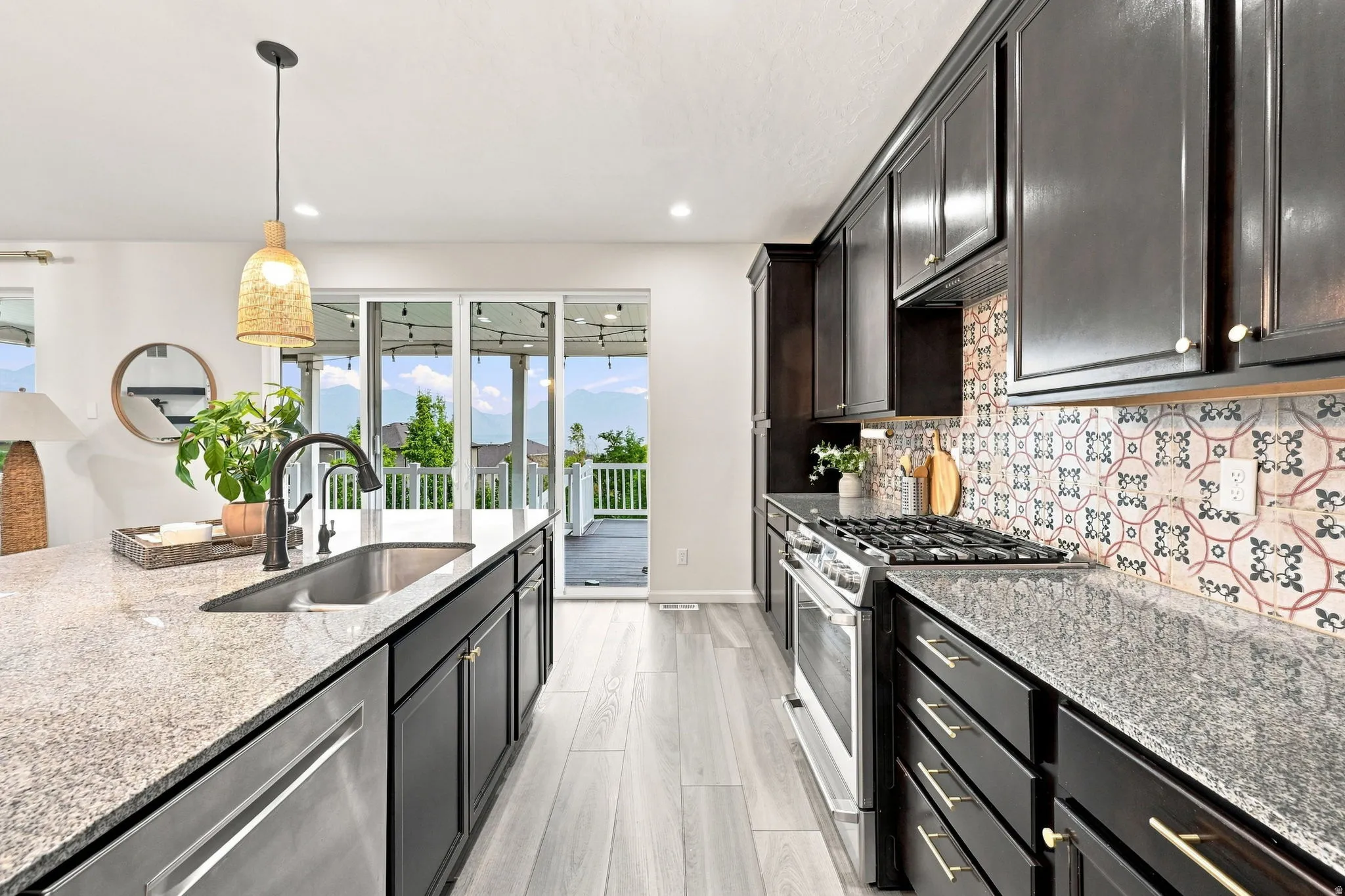 Kitchen featuring dark cabinetry, stainless steel appliances, granite countertops, and patterned tile backsplash