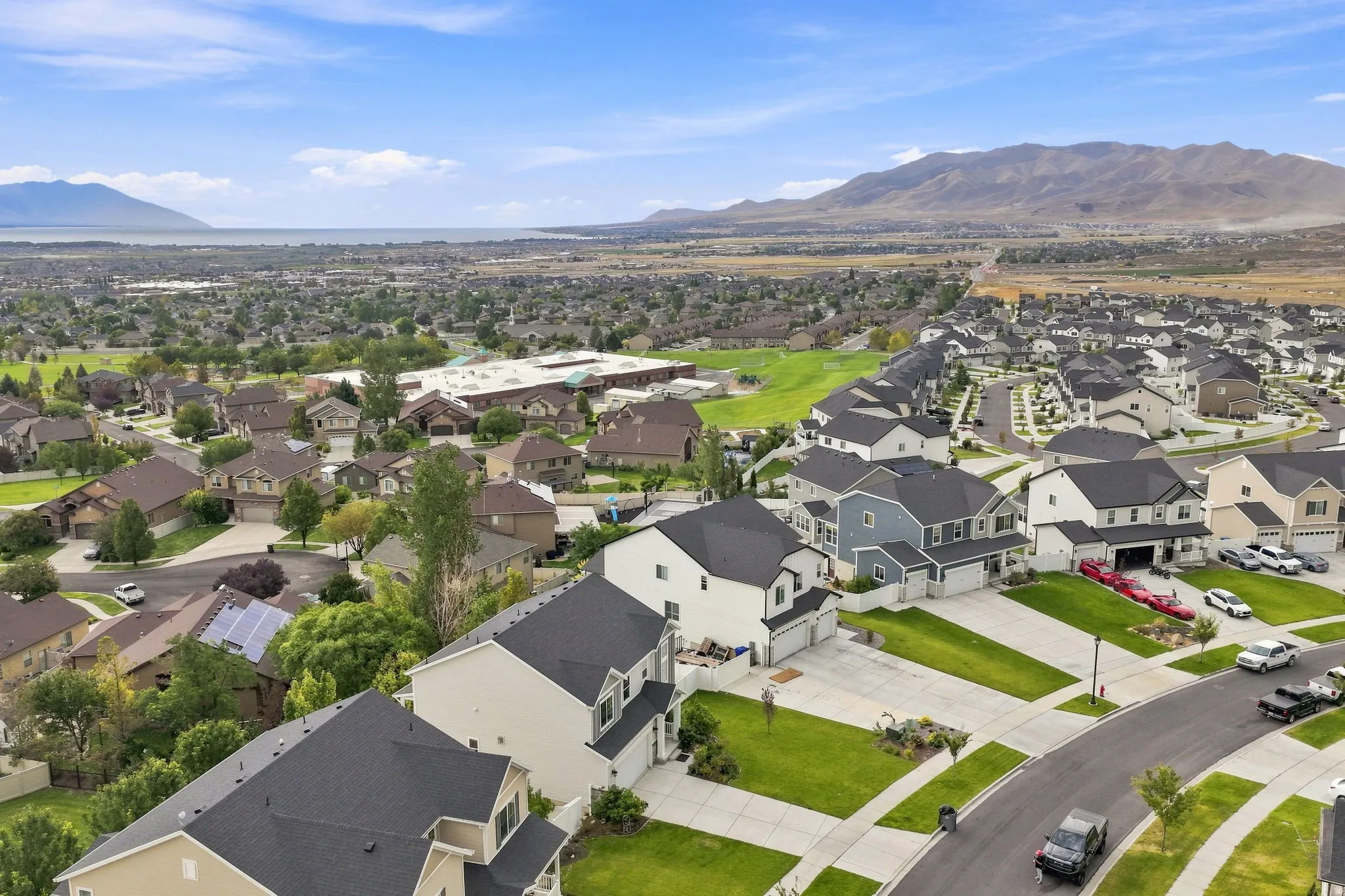 Expansive neighborhood featuring residential homes, paved streets, and green lawns with mature trees