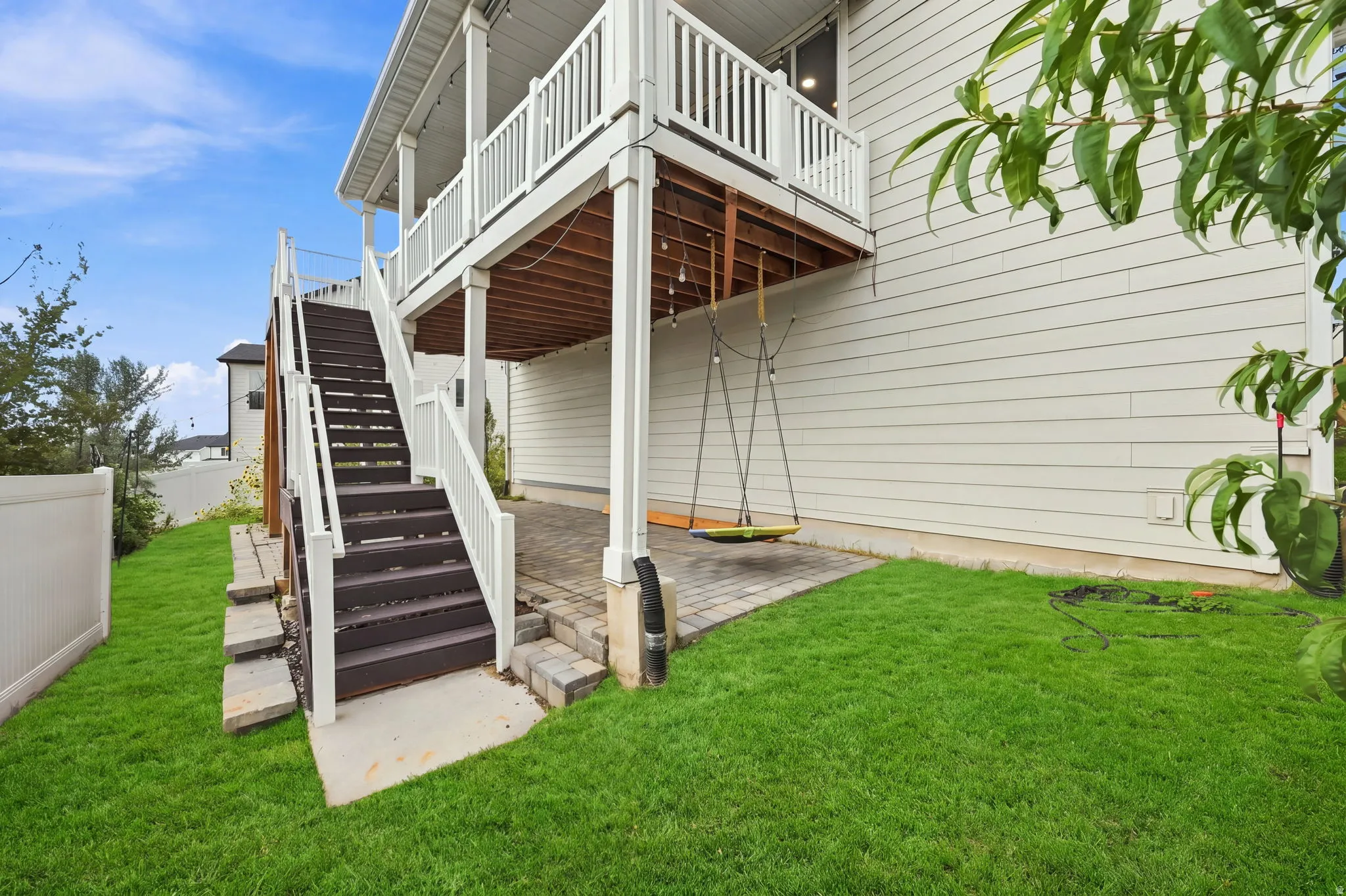 Expansive lawn area with a multi-level deck and staircase, featuring white railings and dark treads
