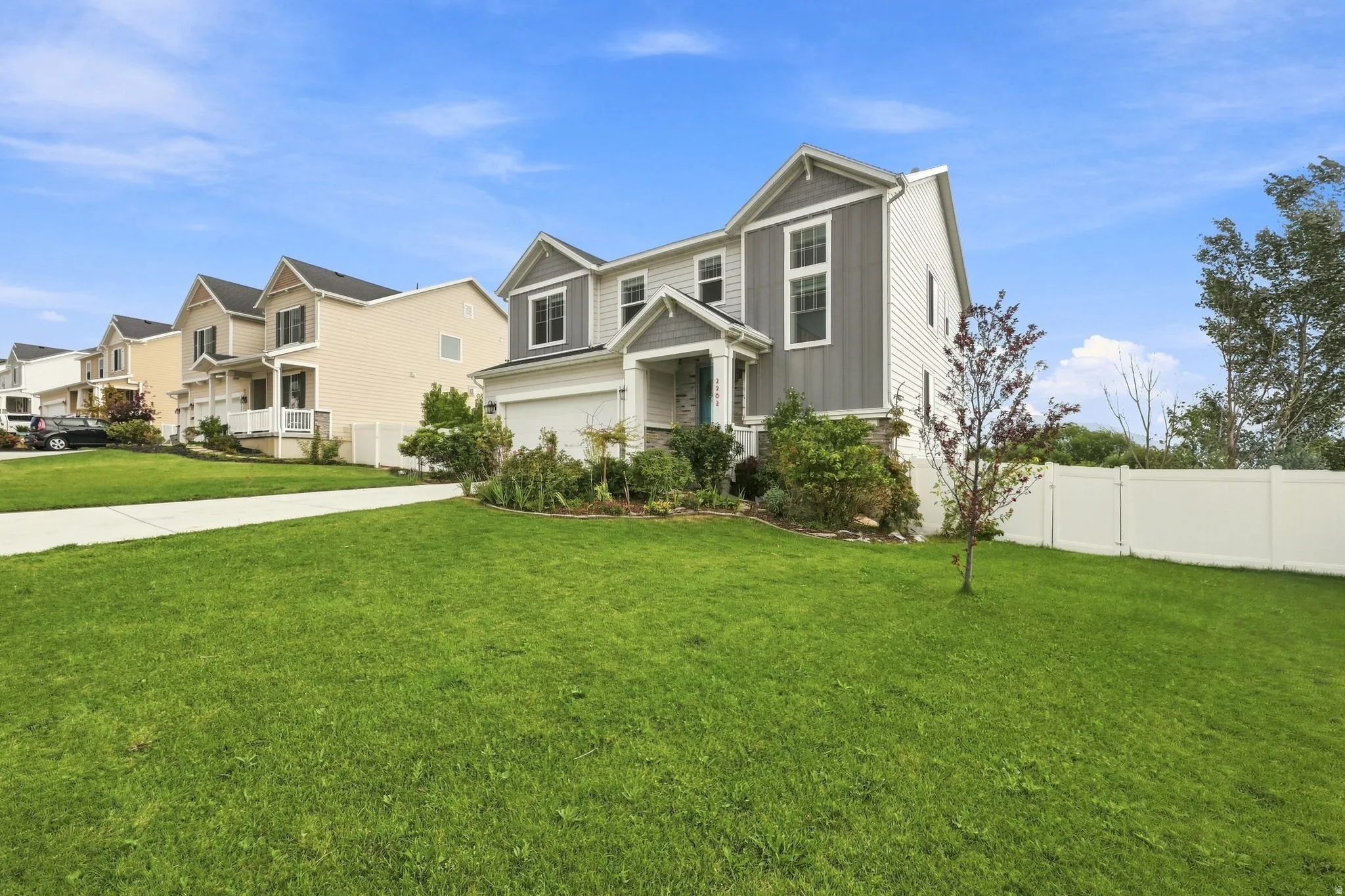 Two-story residence with a multi-textured facade, attached garage, front porch, and a paved driveway