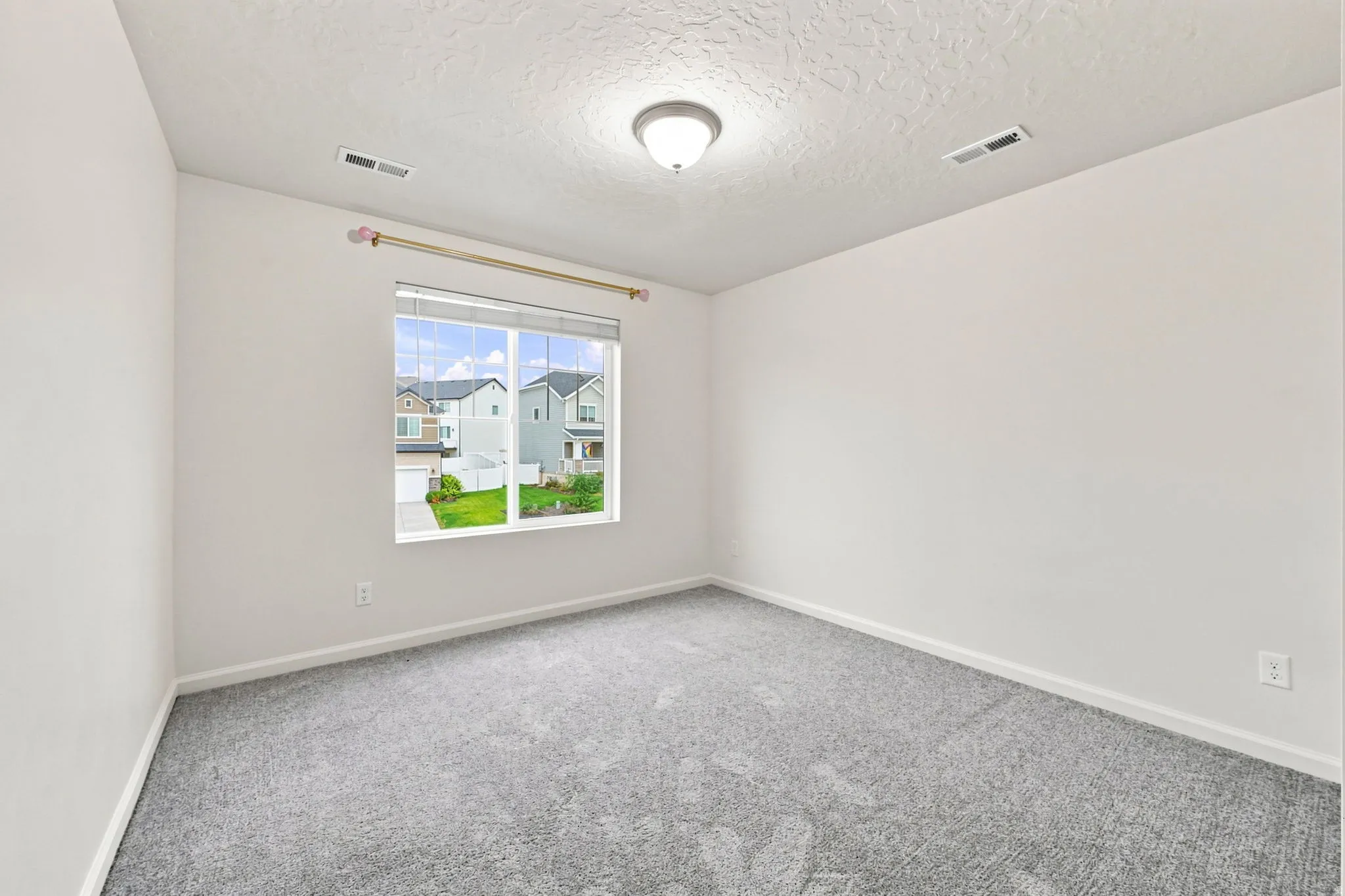 Neutral wall paint, textured ceiling, gray carpeting, dual-pane window, and overhead lighting