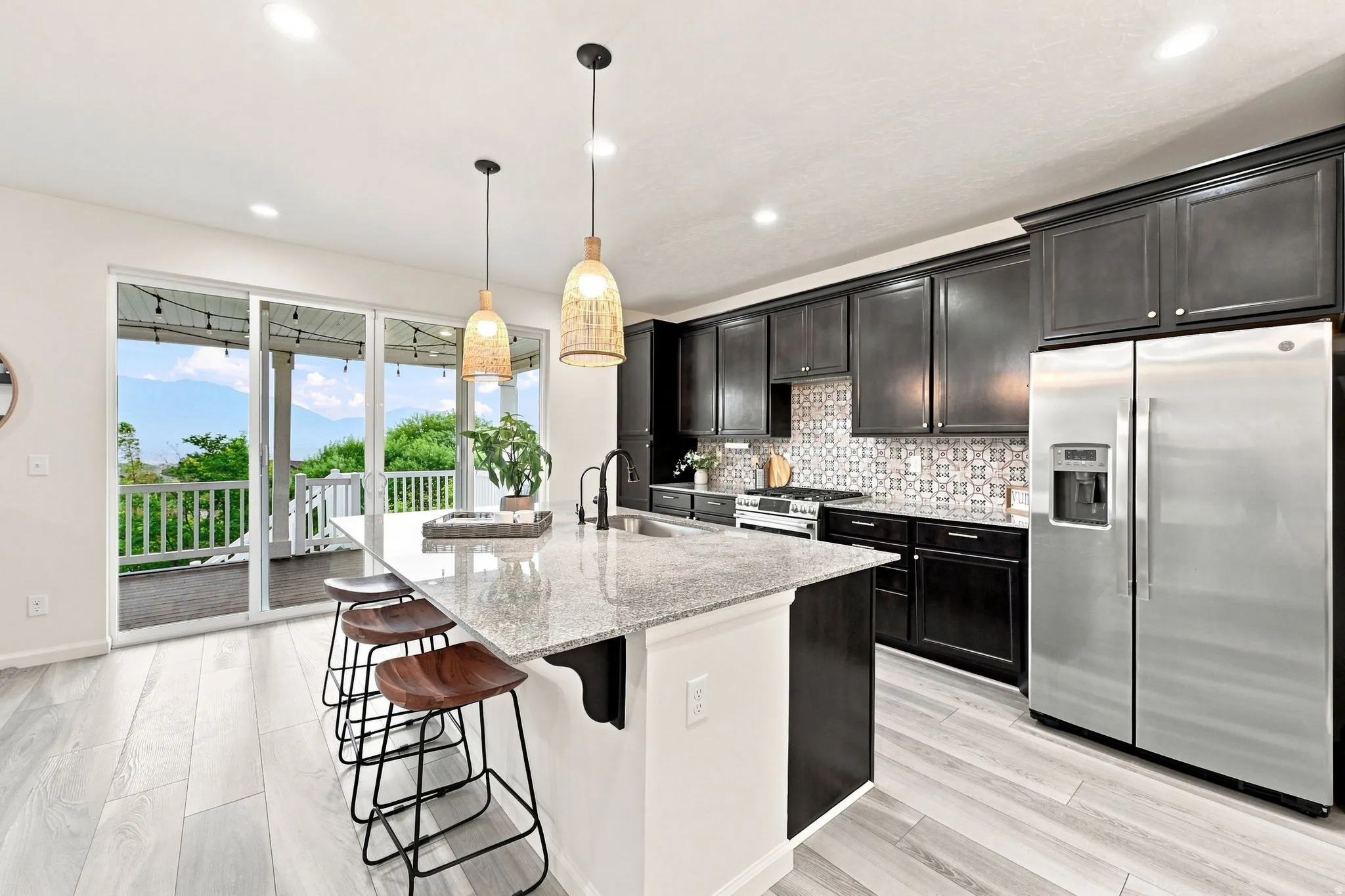 Gourmet kitchen with dark cabinetry, stainless steel appliances, a large center island with a stone countertop, and a decorative tile backsplash