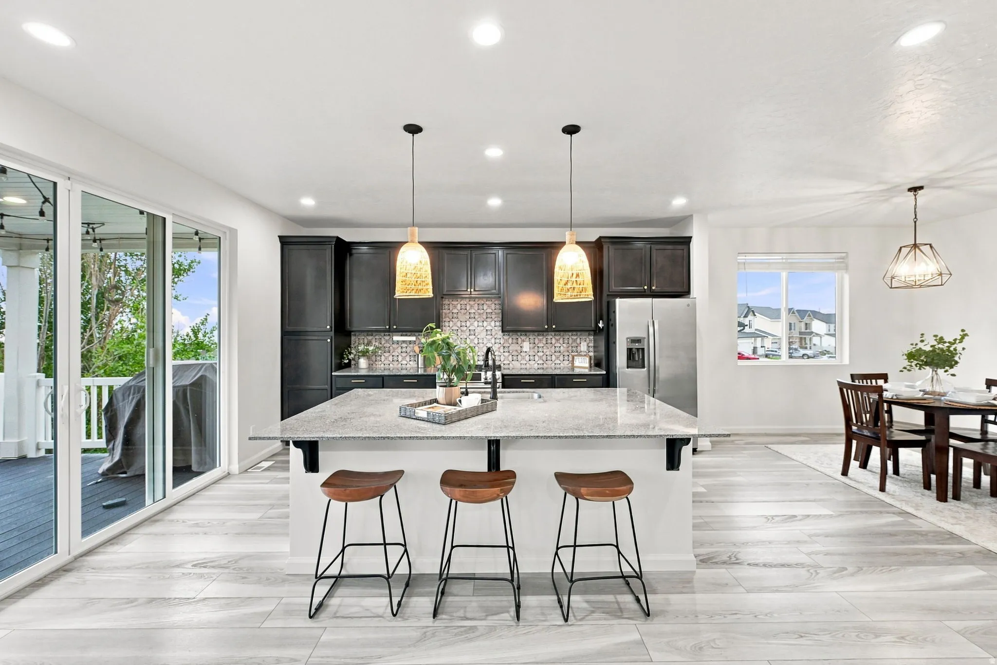 Kitchen featuring dark cabinetry, a center island with a light-colored countertop, and a patterned backsplash