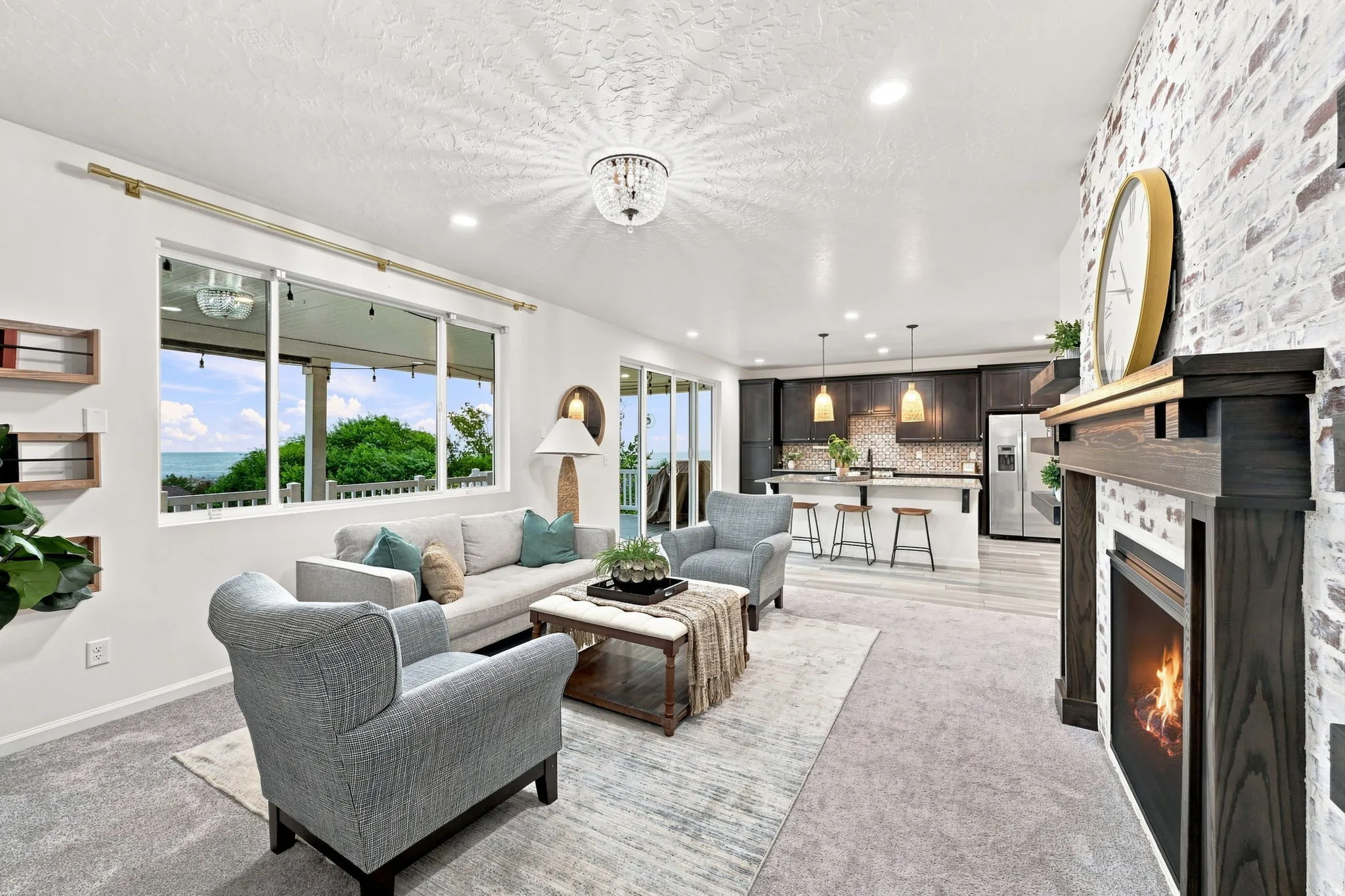 Open-concept living area featuring a fireplace with a wood mantel, a white brick accent wall, and recessed lighting