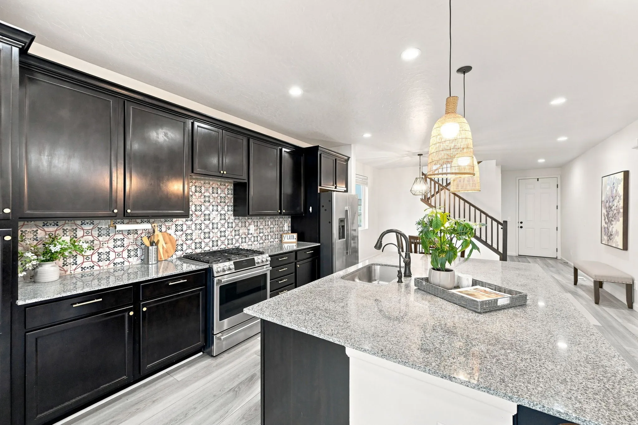 Kitchen featuring dark cabinetry, patterned backsplash, granite countertops, and stainless steel appliances