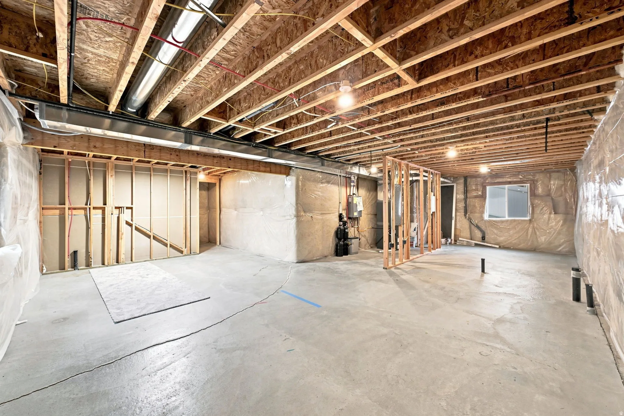 Unfinished basement with exposed ceiling joists, concrete flooring, and framed interior walls