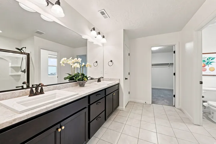 Double vanity with dark wood-finish cabinetry, integrated sinks, and bronze-finish fixtures