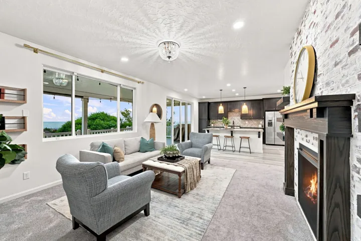 Open-concept living area featuring a fireplace with a wood mantel, a white brick accent wall, and recessed lighting