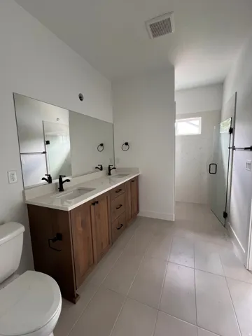 Dual vanity with integrated sinks, light-toned countertop, and dark wood-finish cabinetry