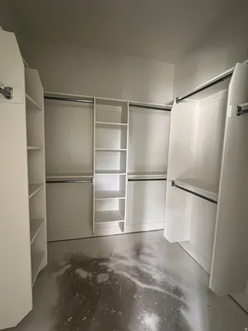 Walk-in closet featuring white built-in shelving, multiple hanging rods, and ample storage compartments