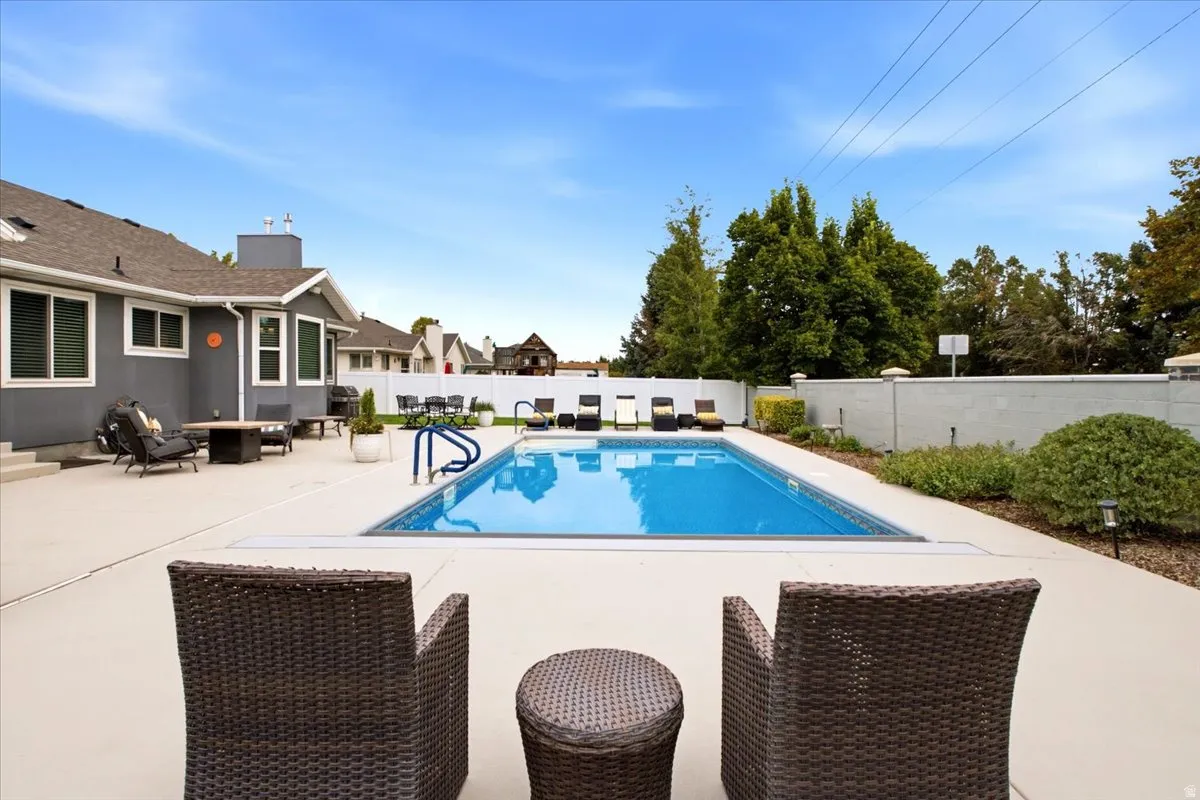 In-ground swimming pool with surrounding hardscaping, a concrete patio, and a stucco exterior