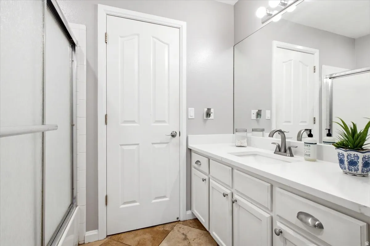 Full-width vanity with white cabinetry, integrated sink, brushed nickel faucet, and a large wall-mounted mirror