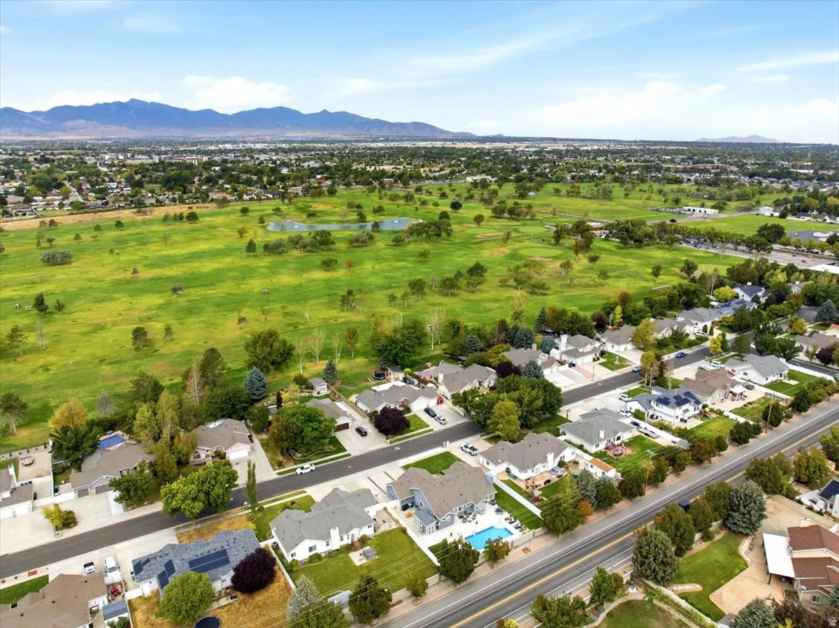 Aerial perspective featuring residential properties, a golf course, and distant mountains