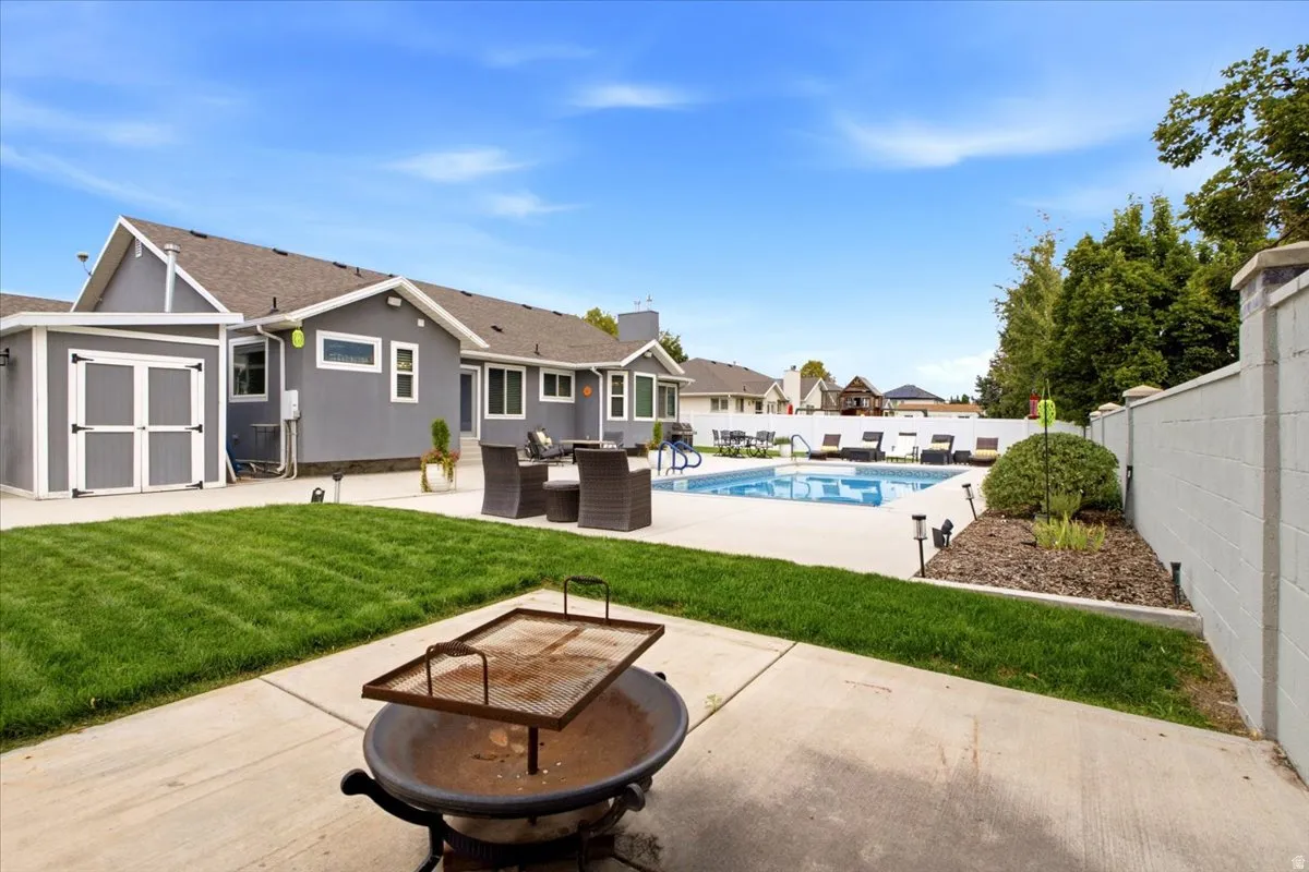 Expansive concrete patio with a fire pit, leading to a private swimming pool