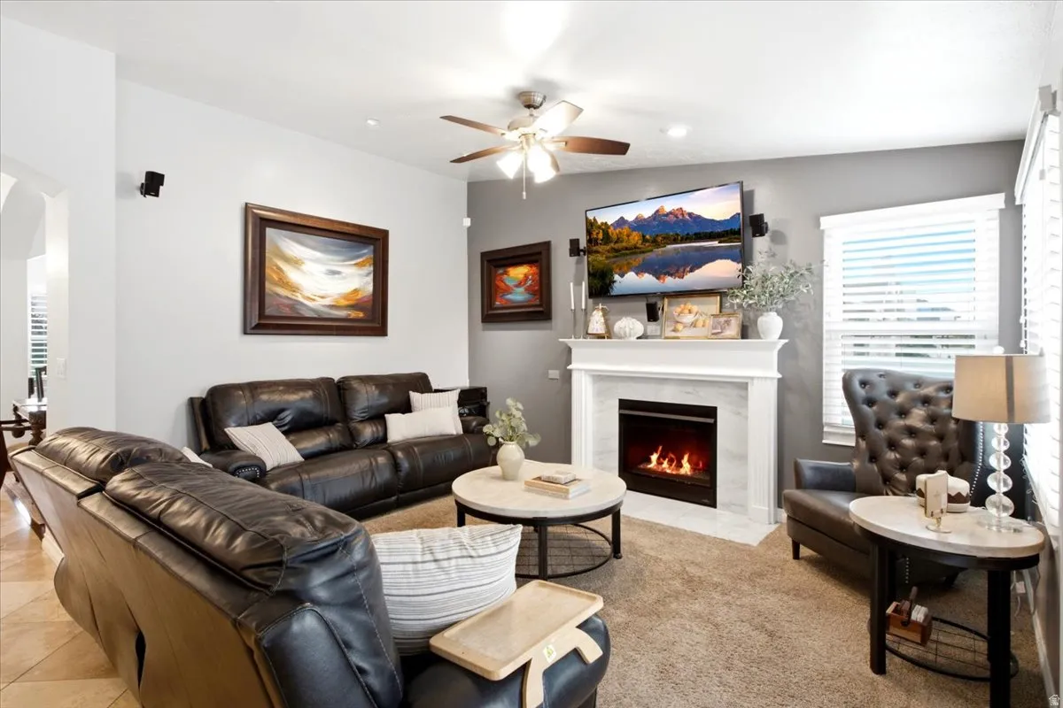 Recessed lighting, ceiling fan, and a fireplace with a white mantel and surround