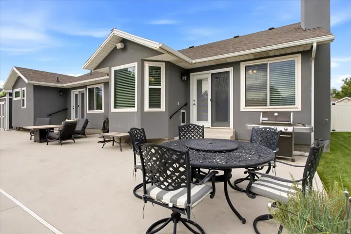 Expansive concrete patio with stucco exterior, multiple windows, and a sliding glass door