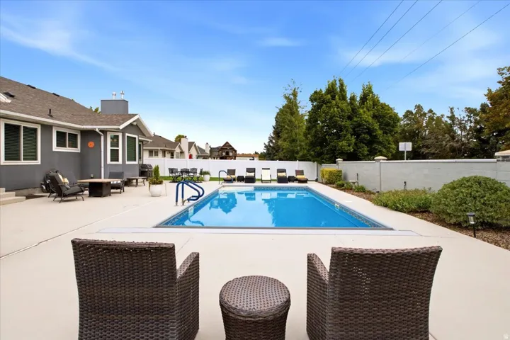 In-ground swimming pool with surrounding hardscaping, a concrete patio, and a stucco exterior