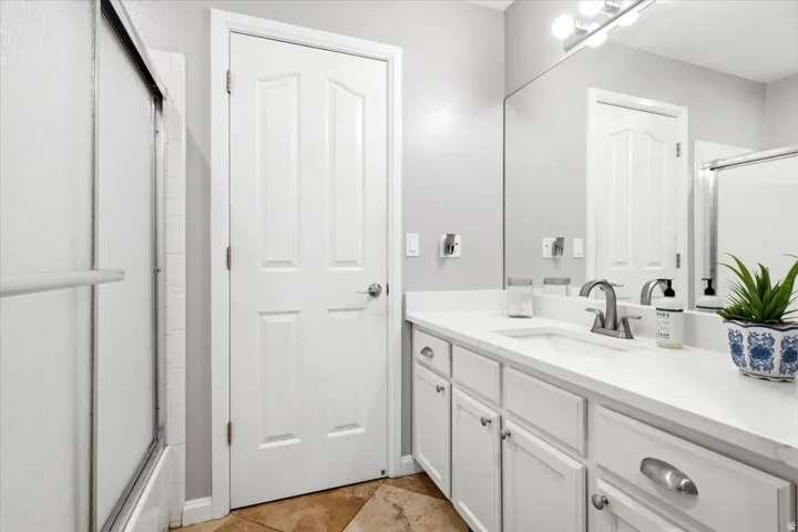 Full-width vanity with white cabinetry, integrated sink, brushed nickel faucet, and a large wall-mounted mirror