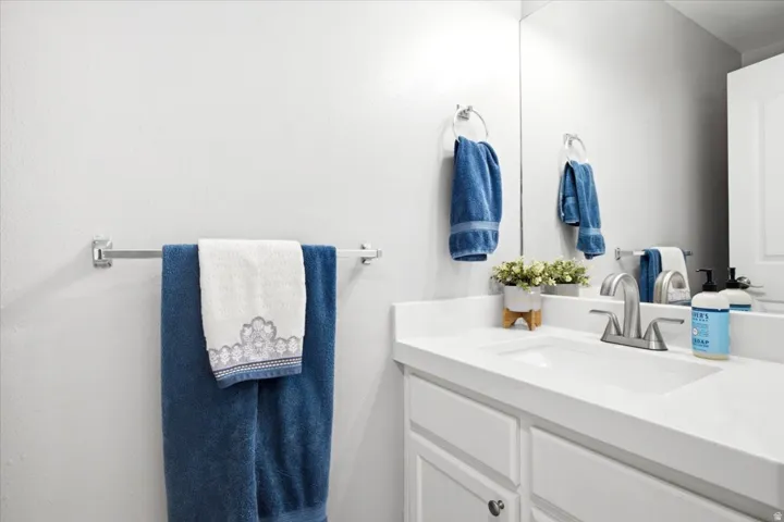 Bathroom featuring an integrated sink, polished chrome faucet, built-in vanity cabinetry, and a wall-mounted mirror