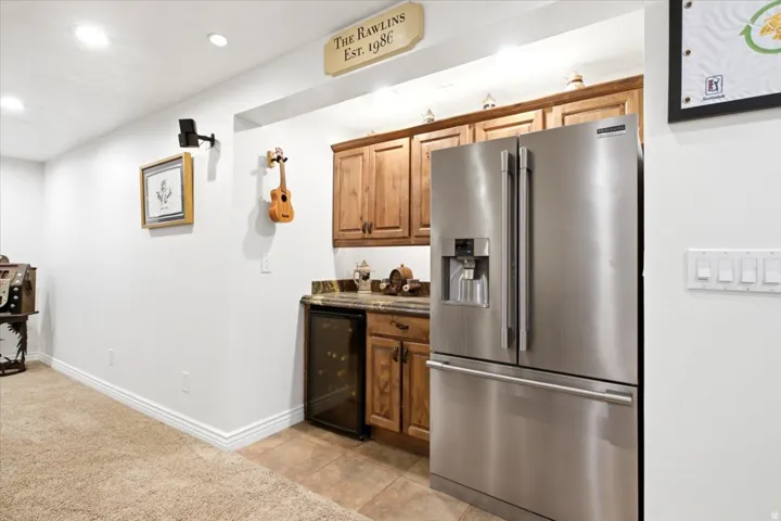 Built-in wet bar featuring wood-finish cabinetry, a stainless steel refrigerator, and a beverage cooler