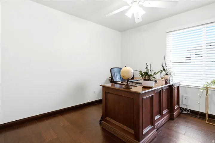 Wood-finish flooring, white walls, and a ceiling fan with integrated lighting